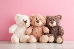 smiling-white-light-brown-and-dark-brown-teddy-bears-sitting-on-table-at-pink-wall-background-pastel-color-togetherness-and-friendship-concept-front-view-closeup-